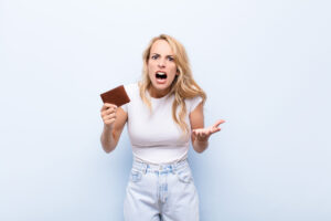 Zdenerwowana młoda kobieta z portfelem w prawej ręce