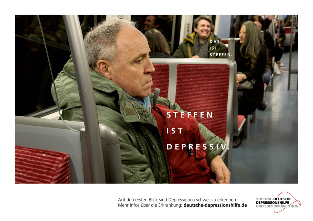 Przygnębiony mężczyzna w kurtce jedzie metrem, jest podpisany "Steffen ma depresję". W tle śmieje się młody chłopak rozmawiający ze swoją towarzyszką podróży, jednak to on jest opisany jako Steffen